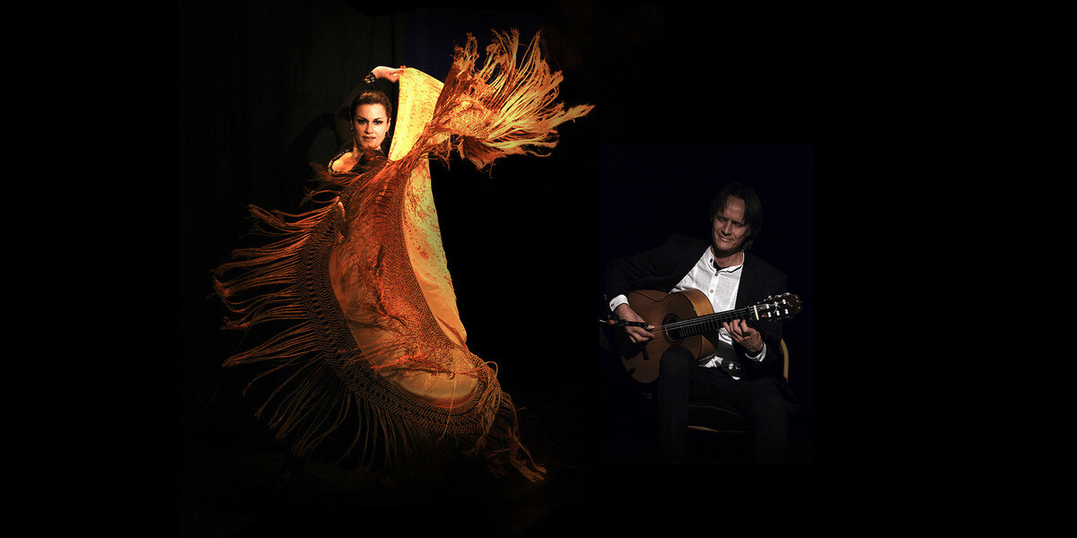Flamencodanza–The flamenco dancer stares fiercely into the camera as her arm whips behind her head, the large red and gold  fringed fabric she holds billowing out in front of her.  To her right, the flamenco guitarist sits in a black suit strumming a guitar, his eyes closed as he listens to the music.