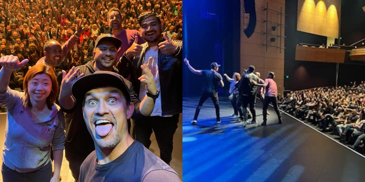 Comedians Ting Lim, Xavier Susai, Ivan Aristeguieta, Dilruk Jayasinha, Andy Saunders, and Joe White pose on stage for a selfie with a cheering, packed theatre audience after a live stand-up show. The performers are smiling and gesturing enthusiastically under bright stage lights, celebrating a sold-out FRINGE WORLD Perth event.