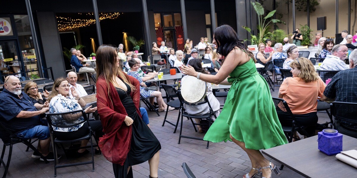 An Italian traditional dancer and a lady with a tambourine perform the Tarantella among the tables filled with audience members.