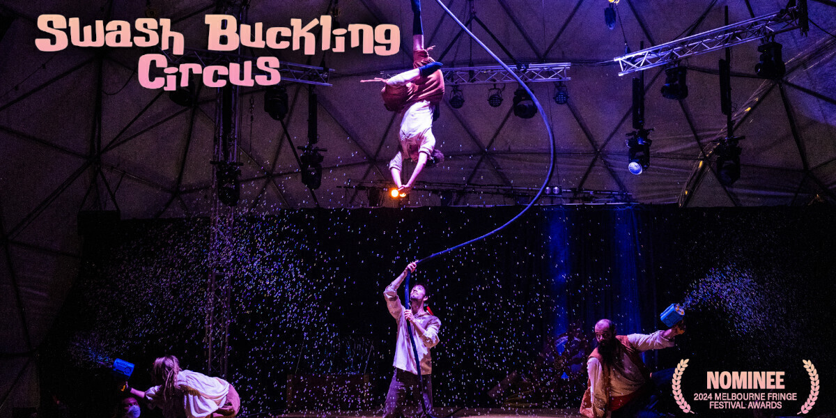 SwashBuckling Circus–an aerialist is hanging from their ankle while bubbles are flying around them. there is another acrobat looking up at the aerialist while two others are crouched in the corners. the scene is dark and muted