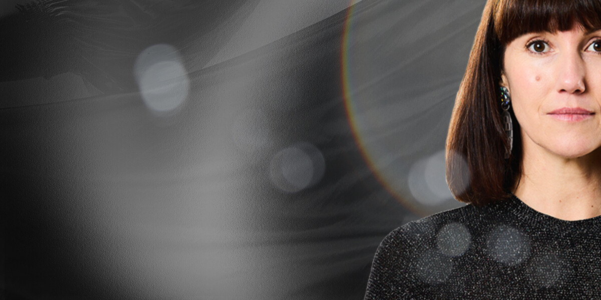 Wright&Grainger's SELENE–A person with mid to long dark hair a bright eyes, and sparkly top looking directly into camera.