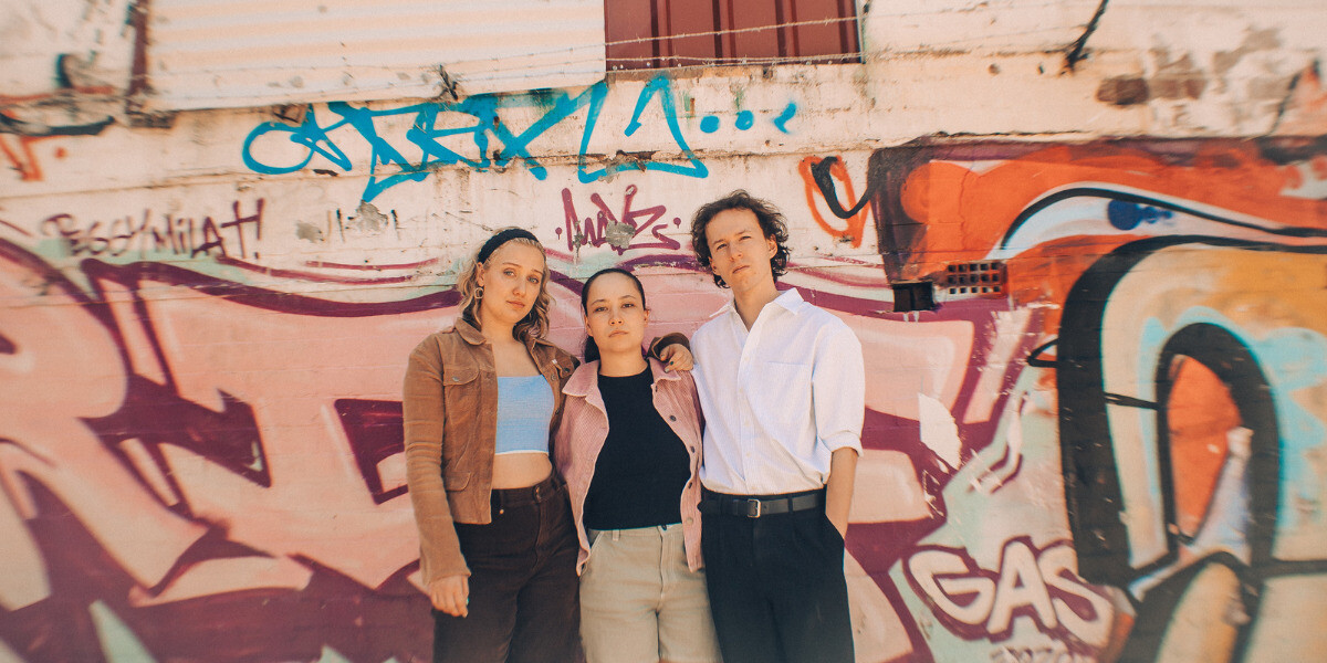 better late, than never.–Someone lies face-down across a bright red couch, one arm dangling toward the floor and their head resting on a white pillow, giving the impression of deep exhaustion or dramatic flop energy.