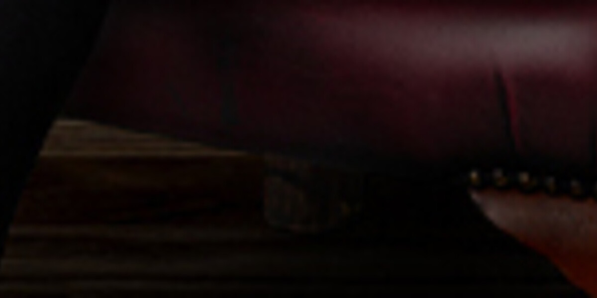 Dom Chambers: Magic Hunt–Man reclining in a burgundy leather armchair against dark green wall panelling, rifle resting across his lap and a whisky tumbler in hand. Above him hangs a faux white rabbit head wearing a bow tie and tiny top hat, creating a surreal, theatrical trophy-room mood.