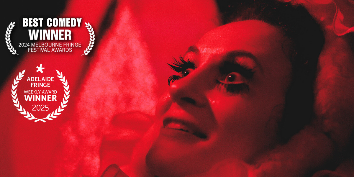 CVNT–CVNT's face bathed in red light with wide eyes with large fake eyelashes