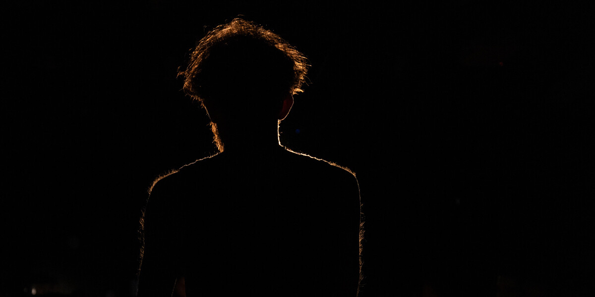 A man with scruffy hair stood with his back to the camera, with an orange glowing silhouette around him