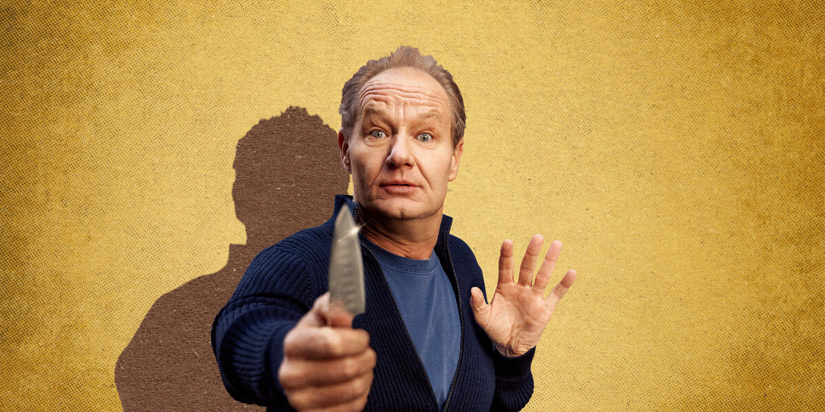 VIRGIN IN A KNIFE FIGHT–“Rob Carlton holding a knife with a surprised look against a yellow background — humorous and theatrical.”