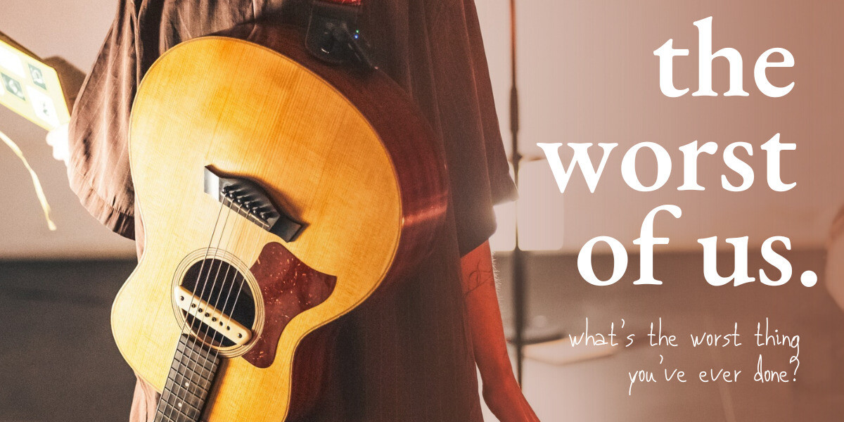 a guitar is strapped to the back of a person facing away from the camera. only their torso is in view, but a journal can be seen open in their left hand. over the top of the left side of the image reads the heading 'the worst of us.' in large serif font, and the subheading 'what's the worst thing you've ever done?' in a smaller handwritten font.